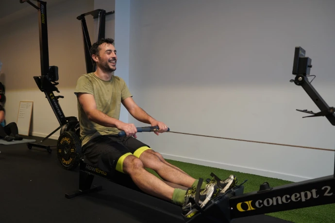 Sportif sur rameur chez BPM Studio Sportif qui fait du rameur en souriant sur le plateau sport de BPM Studio