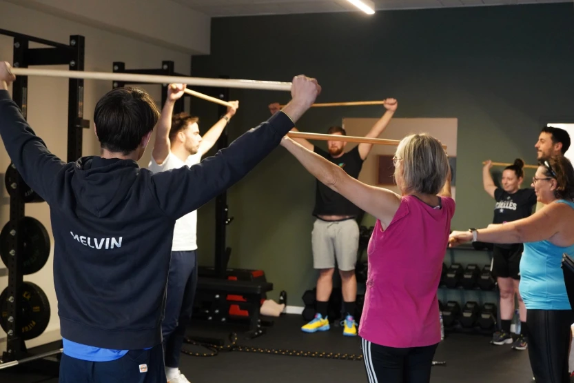 Photo de 6 personnes qui s'échauffent avec un bâton en bois face au coach benjamin dans BPM Studio