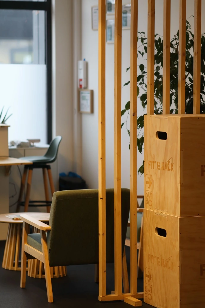 Accueil BPM Studio Photo de l'accueil de BPM Studio. Table en bois, fauteuil vert et box en bois.
